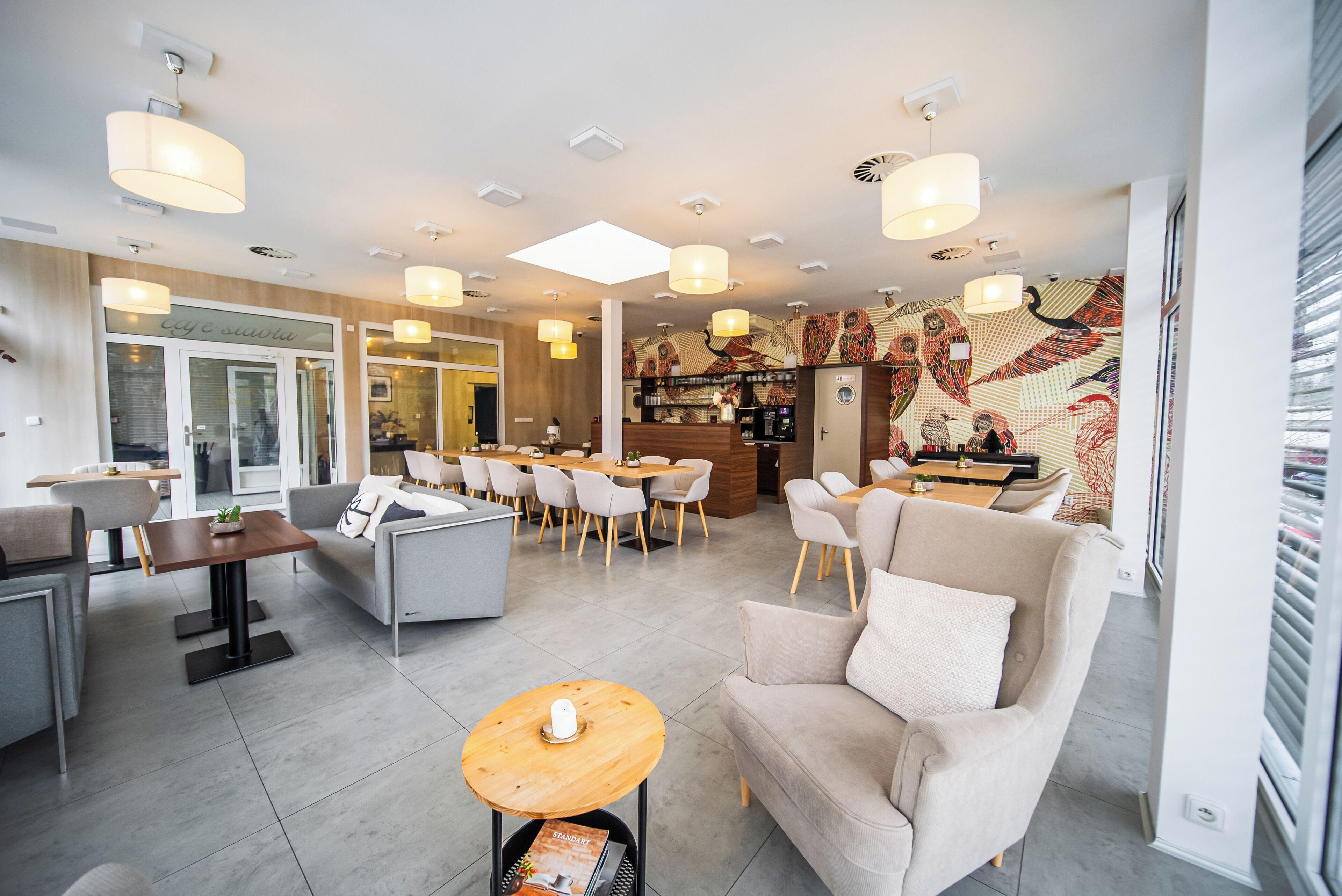 A modern hotel lobby with a seating area, a bar, and a patterned wall.