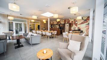 A modern hotel lobby with a seating area, a bar, and a patterned wall.