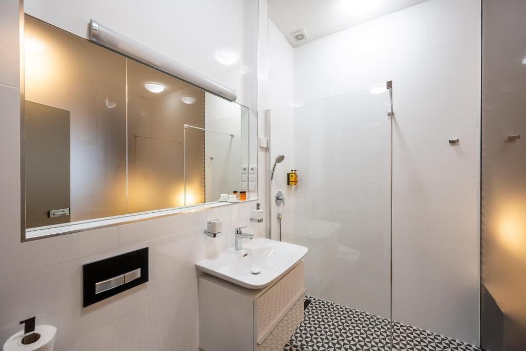Un baño moderno con un espejo grande, un lavabo y una ducha.