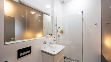 Un baño moderno con un espejo grande, un lavabo y una ducha.