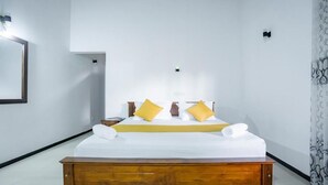 A hotel room with a wooden bed frame, white bedding, and two yellow pillows. - Villa Amora Hikkaduwa (Hikkaduwa)
