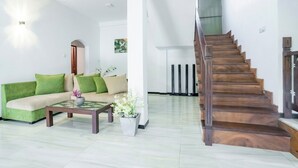 A modern living room with a green sofa, a wooden coffee table, and a staircase with wooden steps. - Villa Amora Hikkaduwa (Hikkaduwa)