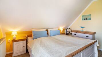 Een slaapkamer met een bed, nachtkastjes, een lamp, een dressoir en een aan de muur hangend schilderij.