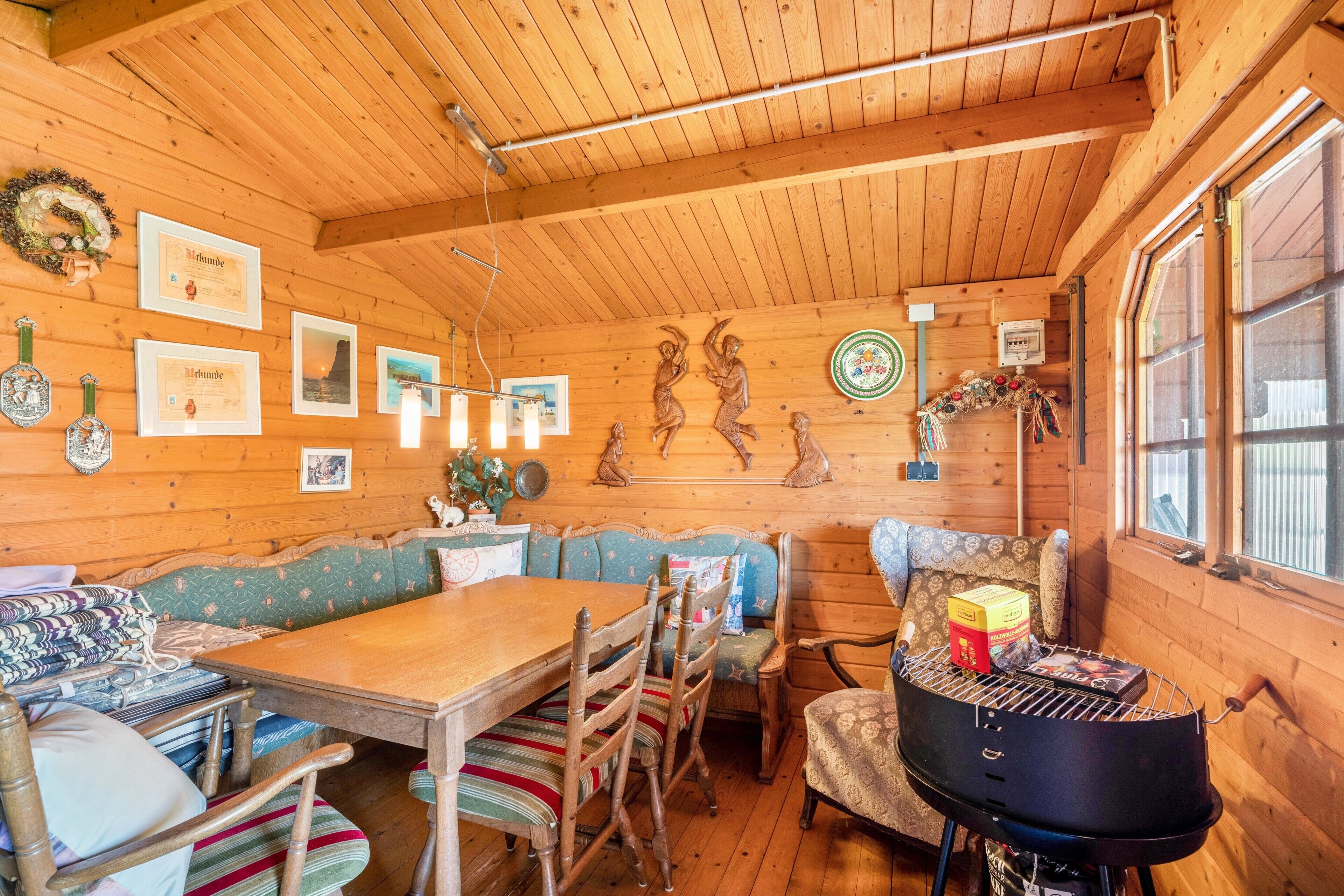 L’intérieur d’un chalet en bois comprend une table à manger, des chaises, un banc et un barbecue.