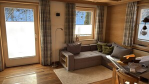 Ein gemütliches Wohnzimmer mit grauem Sofa, einem kleinen Tisch und Karottenvorhängen.