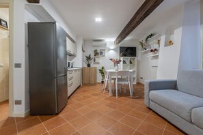 Et lille køkken med køleskab, et spisebord med stole og en sofa.