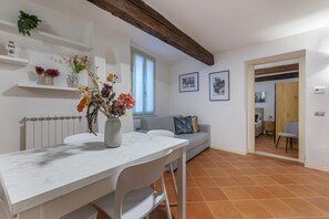 Een moderne keuken met witte kasten, een marmeren aanrecht en een eethoek met een witte tafel en stoelen.