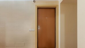 A closed wooden door with a simple handle, a light switch, and a vent above it. - GuestHost - Charming 53sqm apartment, ideal for groups of up to 5 guests, located on the first floor of a historic building without an elevator.Set in the heart of the historic centre, the accommodation is located on one of Ferrara’s most charming medi (Ferrara)
