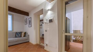 A living room with a sofa, a door leading to a balcony, and a tiled floor. - GuestHost - Charming 53sqm apartment, ideal for groups of up to 5 guests, located on the first floor of a historic building without an elevator.Set in the heart of the historic centre, the accommodation is located on one of Ferrara’s most charming medi (Ferrara)