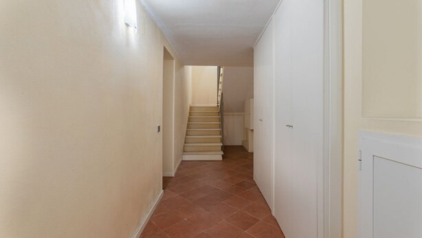 A narrow hallway with a tiled floor, a staircase, and white walls. - GuestHost - Charming 53sqm apartment, ideal for groups of up to 5 guests, located on the first floor of a historic building without an elevator.Set in the heart of the historic centre, the accommodation is located on one of Ferrara’s most charming medi (Ferrara)