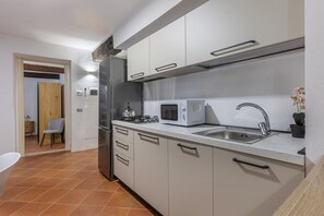 Een moderne keuken met een ingebouwde magnetron, een roestvrijstalen spoelbak en kastjes.
