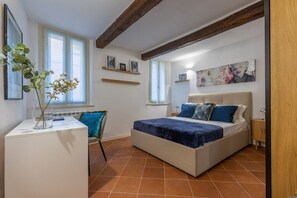 Een slaapkamer met een bed, een bureau, een stoel en een raam.