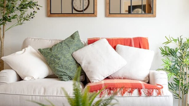 Ein Wohnzimmer mit einer Couch, zwei Spiegeln und einem Couchtisch.