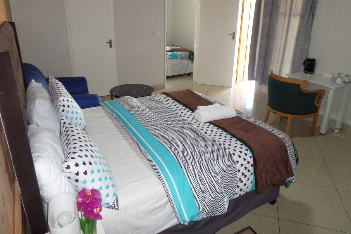 Ein Hotelzimmer mit Bett, Schreibtisch, Stuhl und einem durchgegangenen Tür sichtbaren Badezimmer.