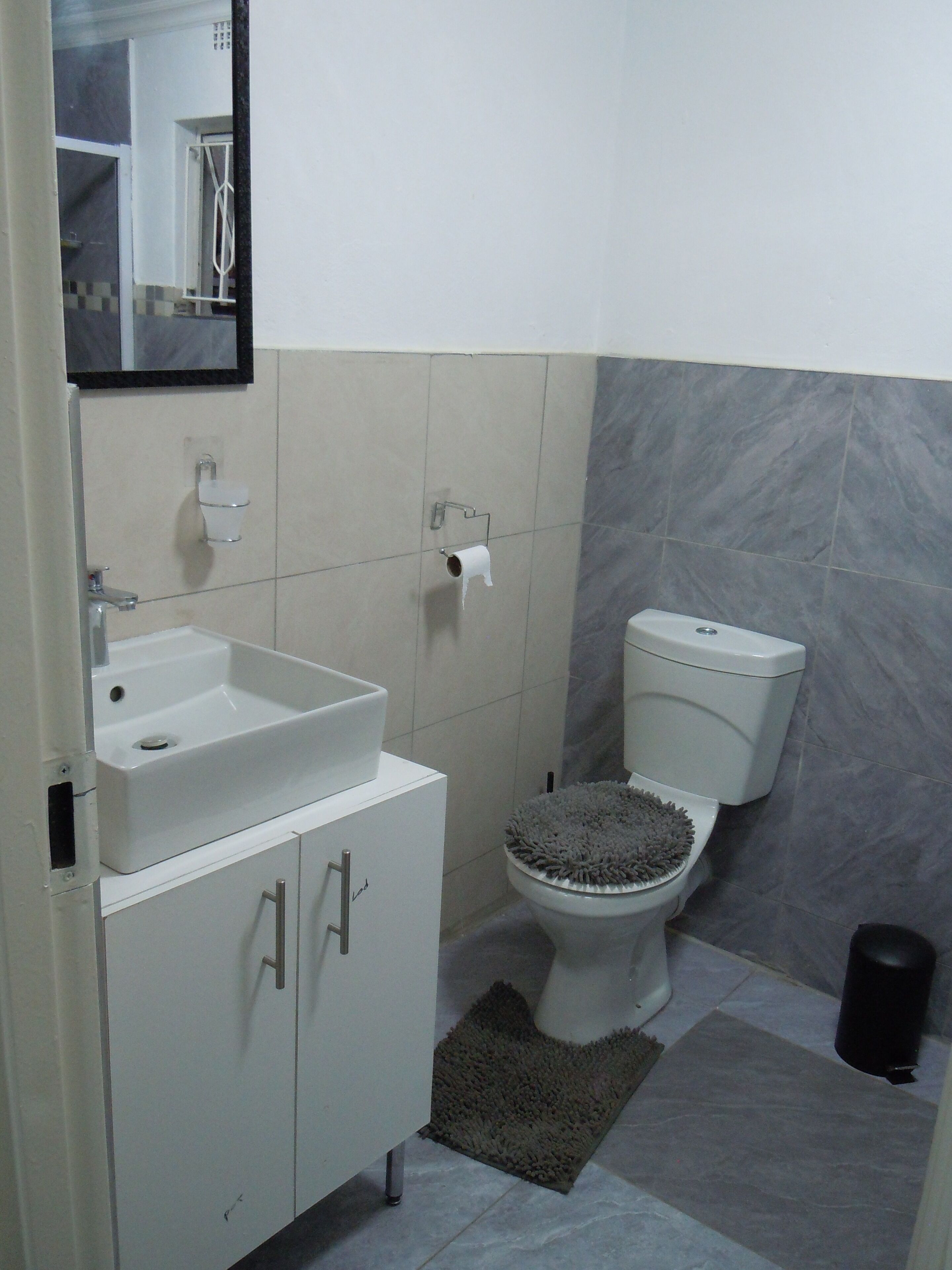 A bathroom with a white sink, toilet, and mirror.