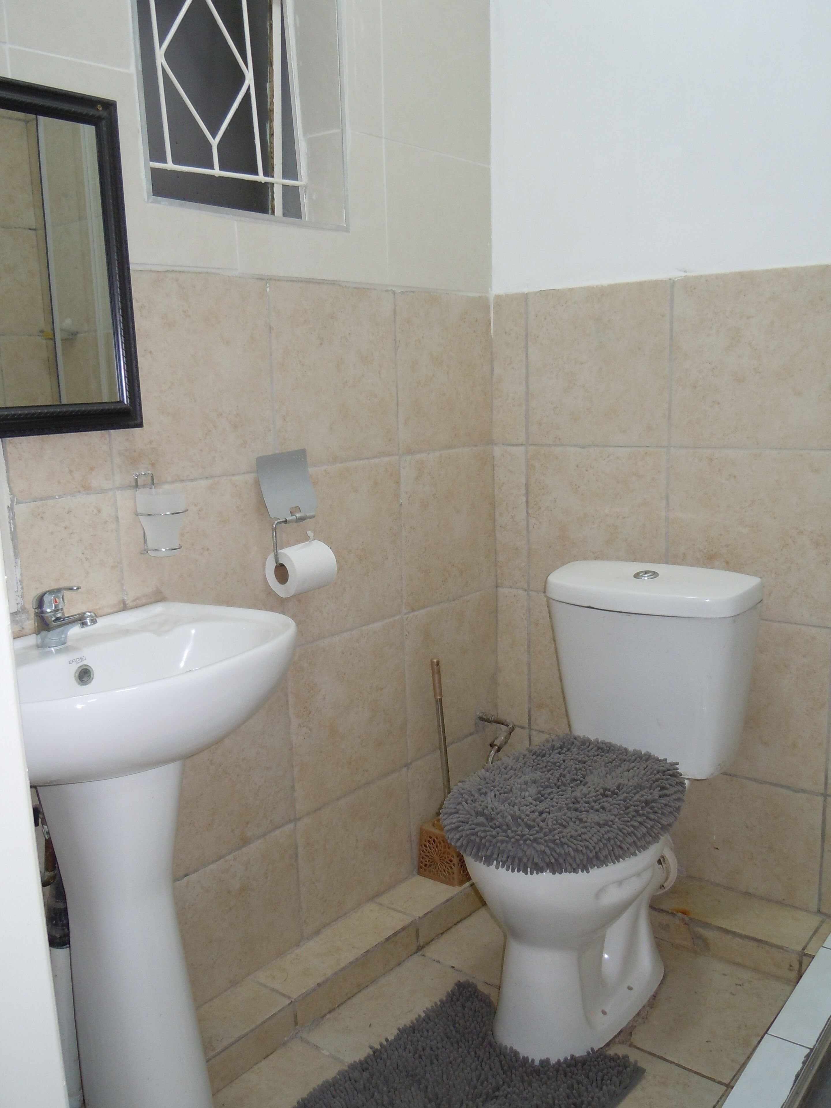 Ein Badezimmer mit Waschbecken, Toilette und einem Fenster mit geometrischem Muster.