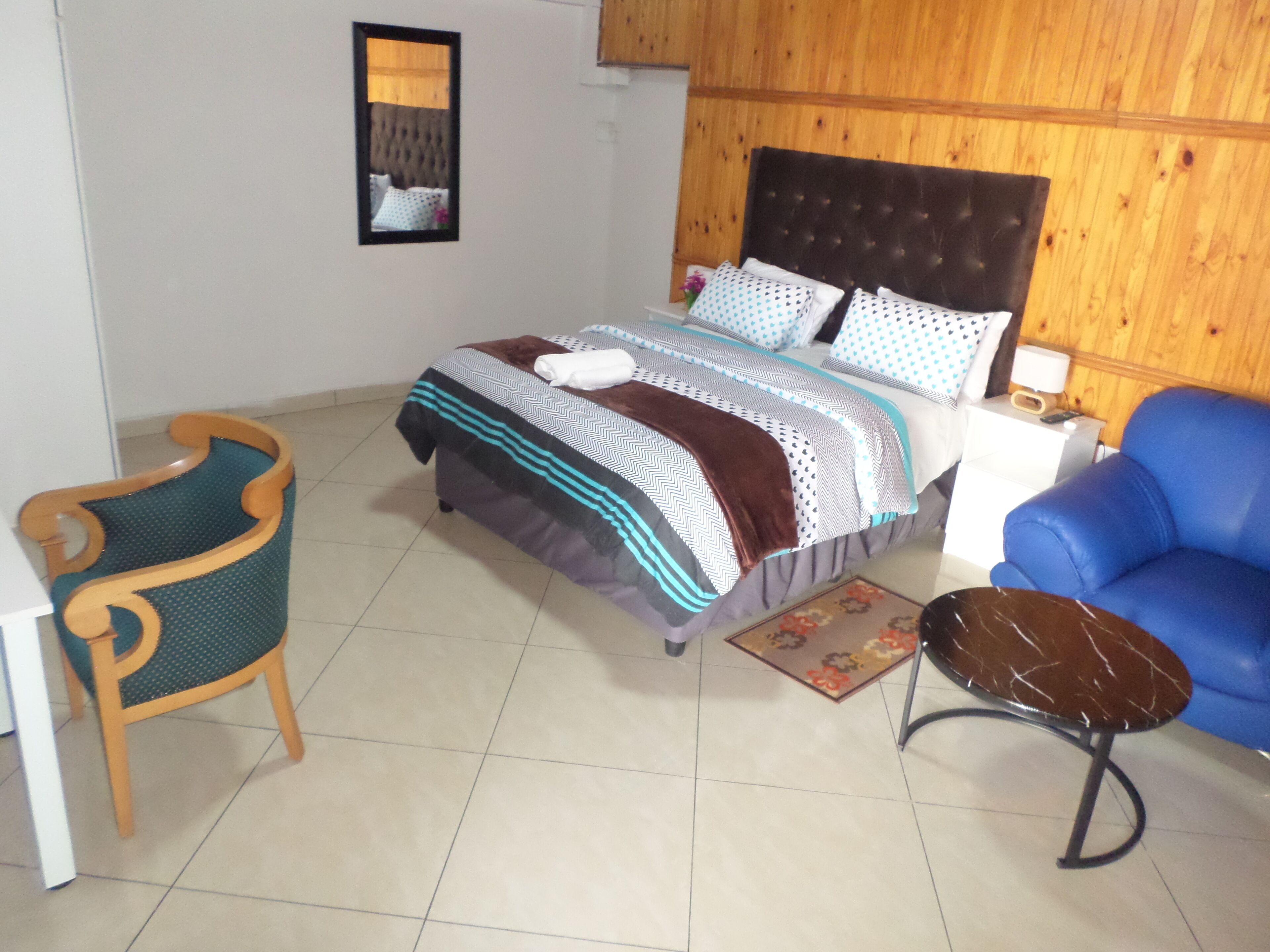 Une chambre à coucher avec un lit, une chaise, un canapé et une petite table.