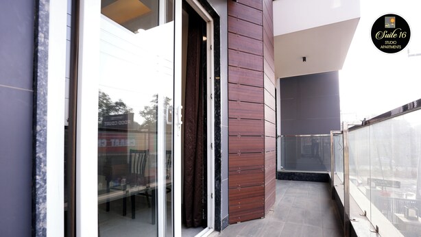 A modern apartment with a glass door, wooden paneling, and a view of the street. - Suite 16 Studio Apartment (Gurugram)