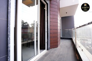 A modern apartment with a glass door, wooden paneling, and a view of the street. - Suite 16 Studio Apartment (Gurugram)