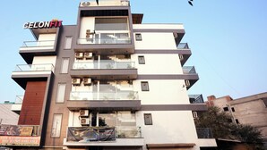 A multi-story building with balconies and a sign for 'GELONFIT' on the facade. - Suite 16 Studio Apartment (Gurugram)