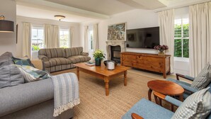 Una sala de estar con sofá, sillón, mesa de centro y televisor.