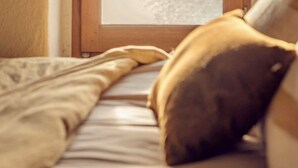 A bedroom with a bed, a wooden door with frosted glass panels, and a window. - CAP Hélios, L'écrin Corse.  Breathtaking sea and pool views (Morsiglia)