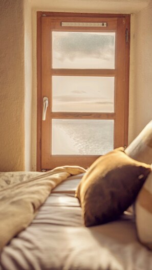 Een slaapkamer met een bed, een houten deur met geëtste glaspanelen en een raam.