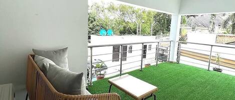 A room with a wicker sofa, a small table, and artificial green grass flooring.