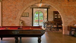 A billiards table in a room with brick walls and an arched ceiling, leading to an outdoor patio area. - Villa Casale Enrica con Piscina Bio Lago (Roccastrada)