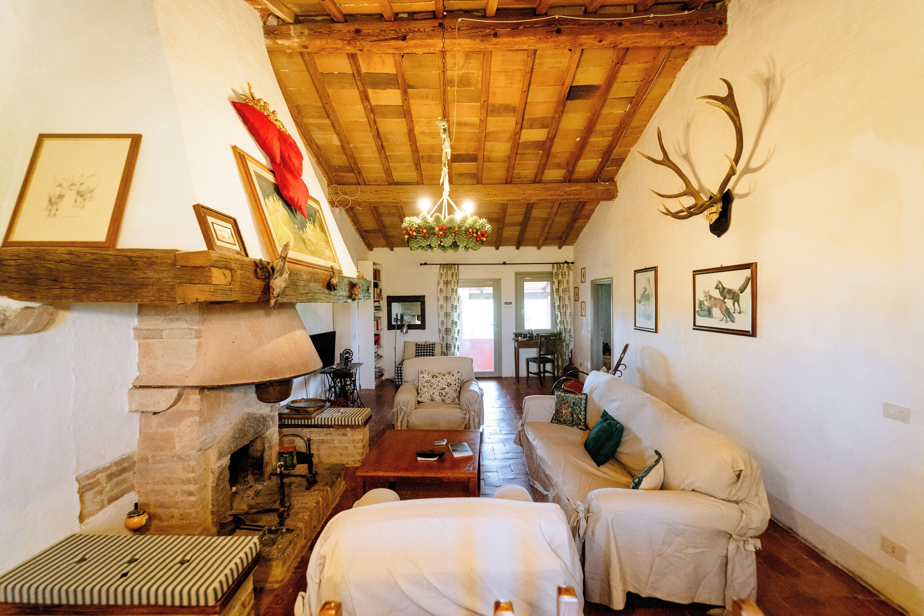 A rustic interior with a wooden ceiling, a fireplace, a sofa, and a chandelier.