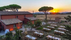A rustic villa with outdoor dining tables set up for an event, surrounded by trees and a sunset view. - Villa Casale Enrica con Piscina Bio Lago (Roccastrada)