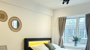 Habitació d'hotel amb dos llits, un finestral gran amb cortines, una planta en test i dos miralls penjats a la paret.