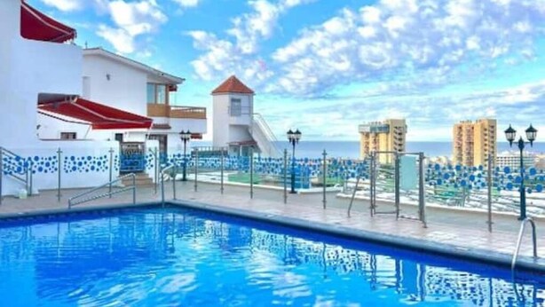 Una piscina con vistas al mar y edificios al fondo.
