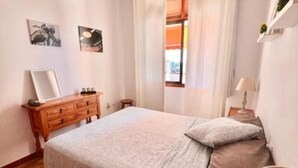 Un dormitorio con cama, cómoda y ventana con cortinas.
