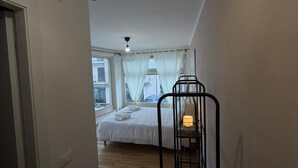 A narrow hallway leading to a bedroom with a bed, a hanging light fixture, and a bedside table with a lamp. - ROOMS 78 (Castel di Sangro)
