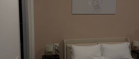 Habitación de hotel con cama, mesita de noche, una obra de arte en la pared y una puerta.