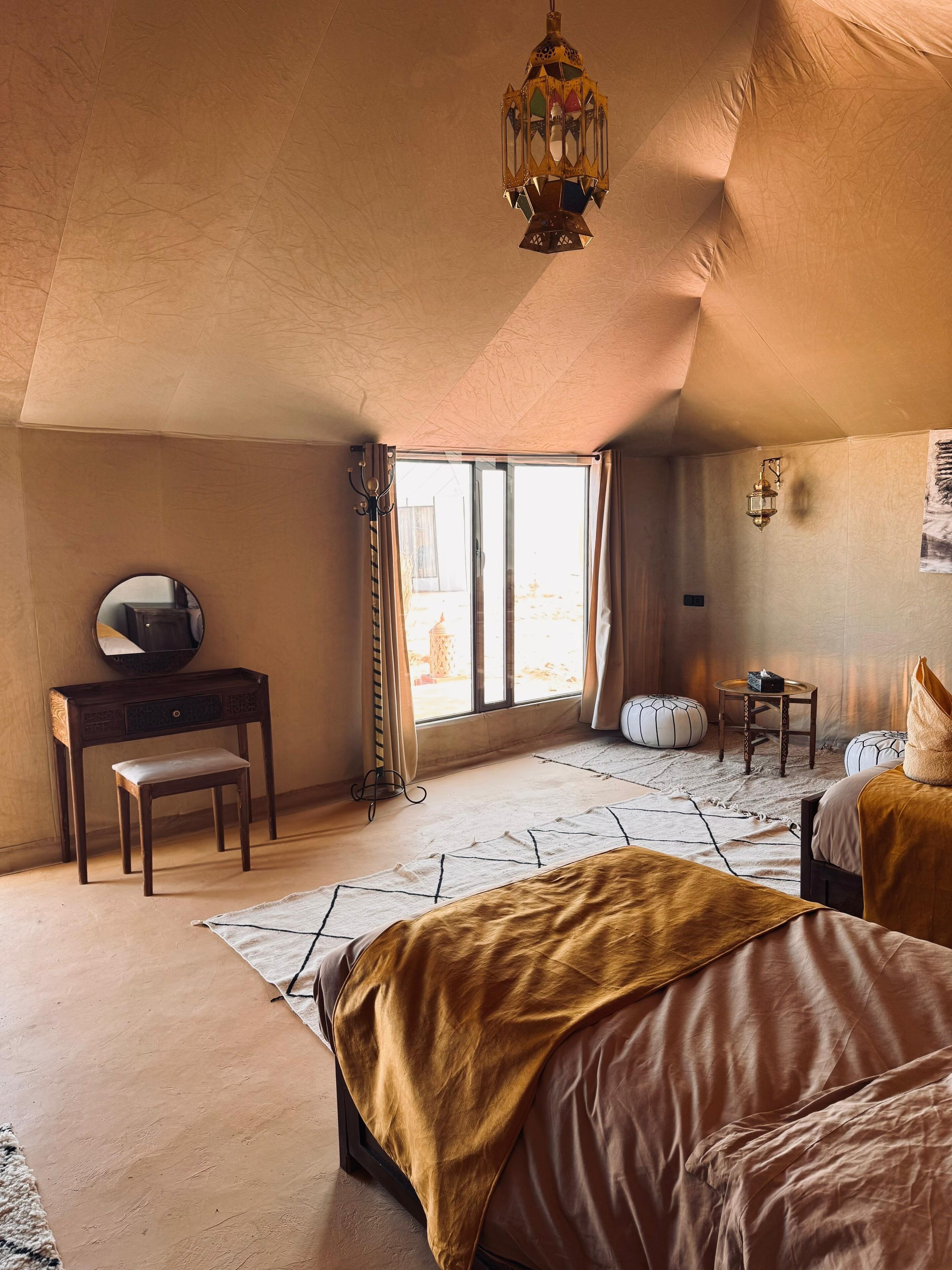 Un dormitorio con cama, escritorio, silla, mesita y lámpara colgante.