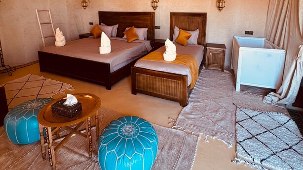 Ein gemütliches Schlafzimmer mit zwei Betten, einem kleinen Nachttisch, einem Babybett und einer hängenden Laterne.