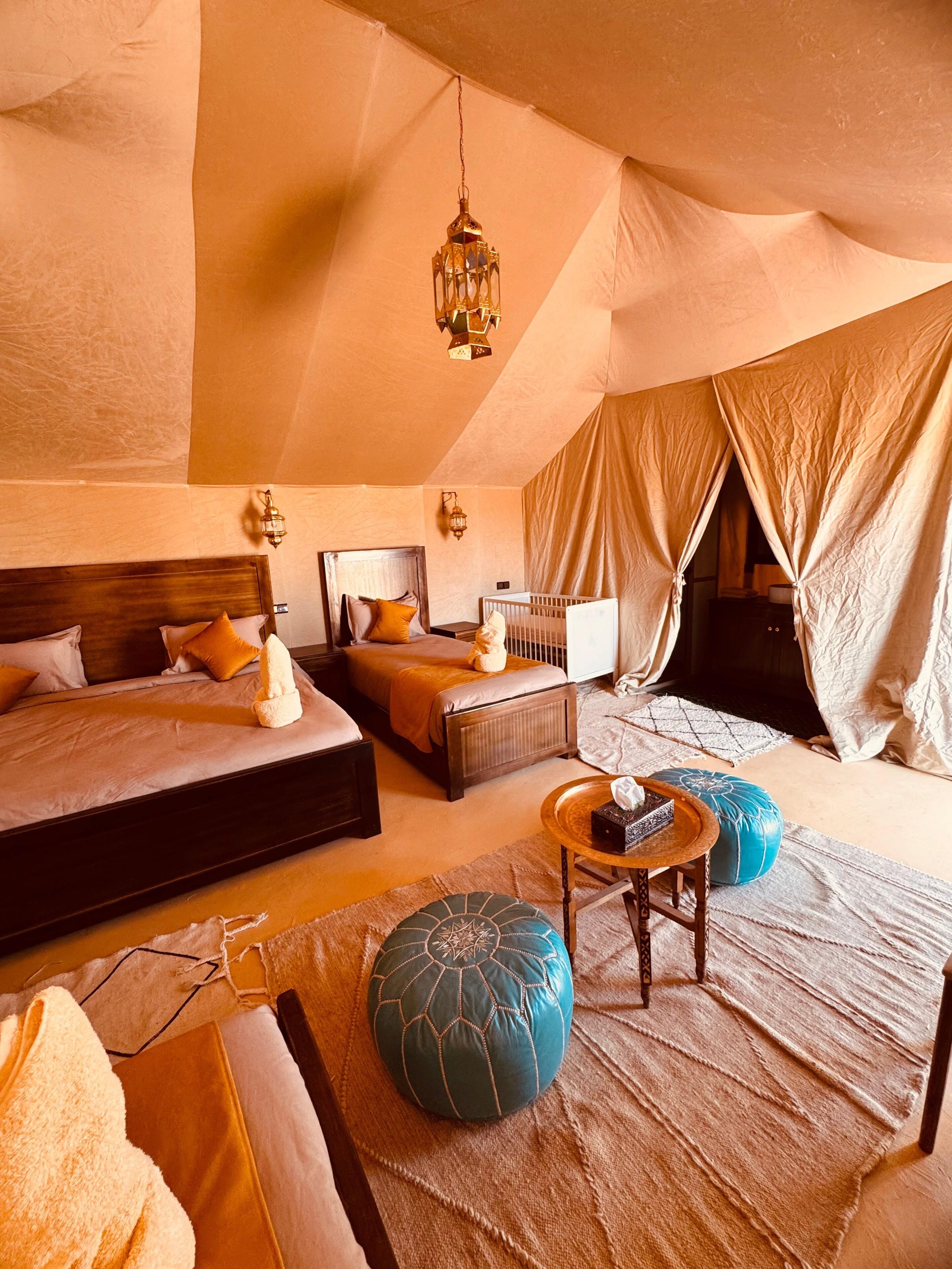 Un dormitorio acogedor con una cama grande, una cama más pequeña y una zona de estar con otomanas.