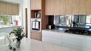 A modern kitchen with wooden cabinets, a built-in oven, microwave, and gas stove. - Modern Seaside Boho Incl Breakfast (Cowes)