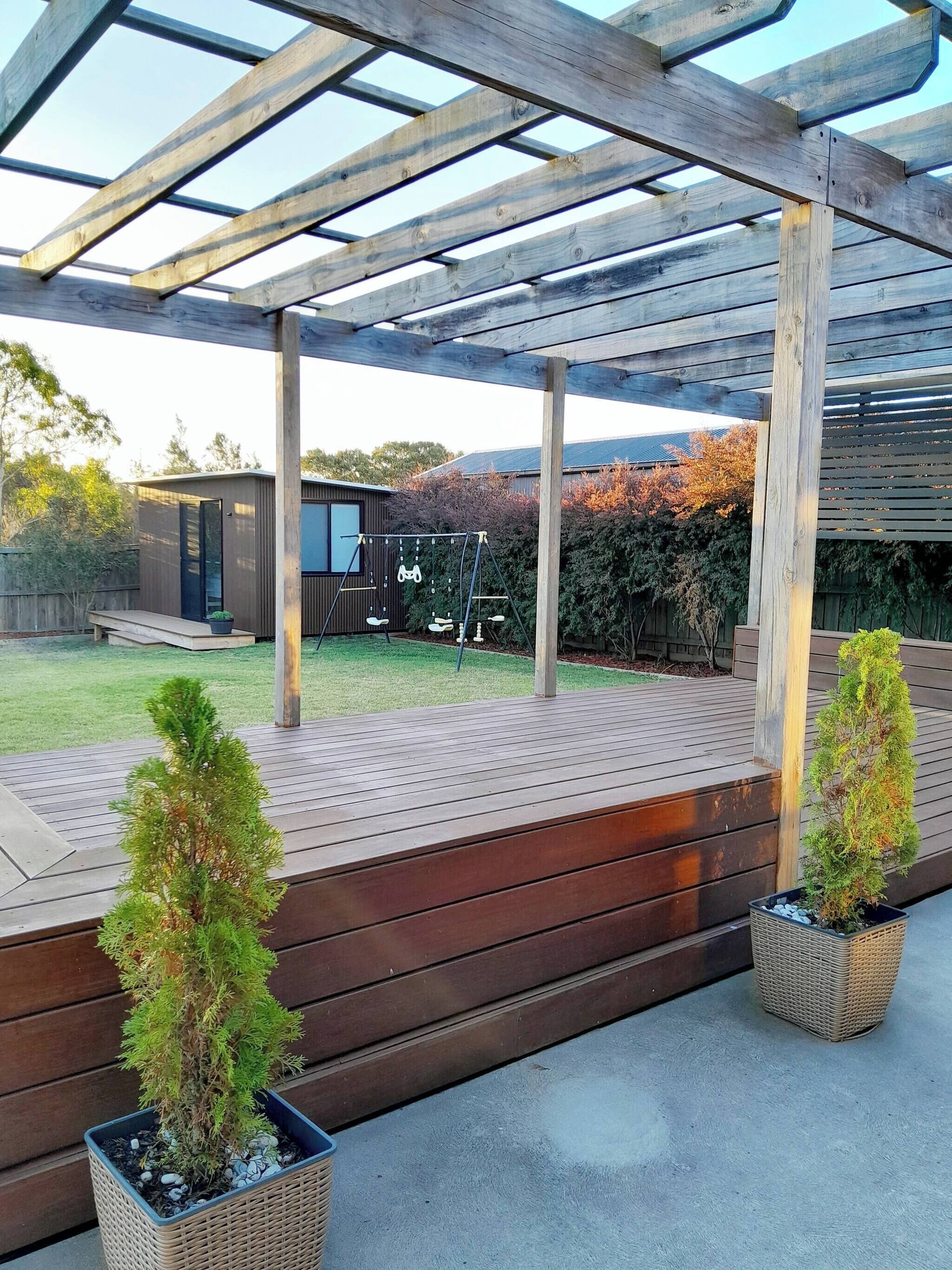 A covered patio area with wooden decking and two potted plants.