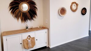 A modern interior with a wooden console table, a decorative mirror, and three wall art pieces. - Modern Seaside Boho Incl Breakfast (Cowes)