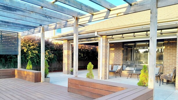 A covered patio area with wooden flooring, seating arrangements, and a brick wall. - Modern Seaside Boho Incl Breakfast (Cowes)