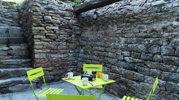 A stone wall with a table and chairs set up for outdoor dining. - Character house in the heart of the baume les messieurs valley (Baume-les-Messieurs)
