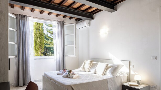 A bedroom with a bed, bedside table, and a window with curtains.