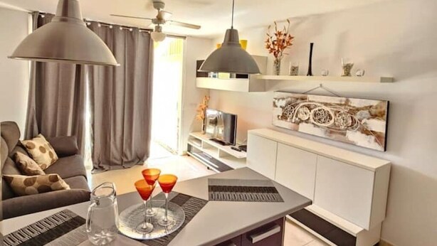 A modern living room with a sofa, a dining table with a tray of drinks, and a ceiling fan. - Nicpa atico Los Cristianos (Los Cristianos)