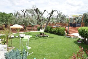 Ein gepflegter Garten mit Rasenfläche, einer Sitzgelegenheit und einer Holzterrasse.