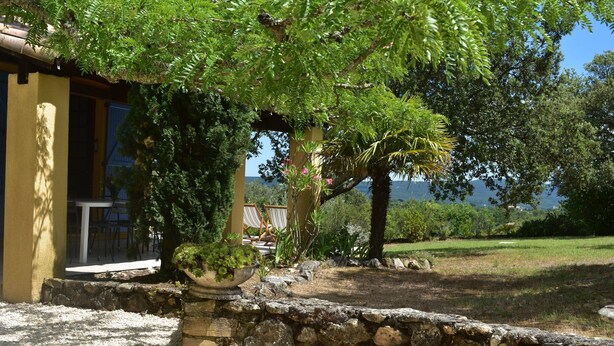 Un muro de piedra con una jardinera, asientos al aire libre y vistas al mar.