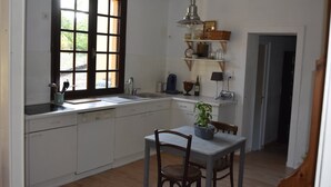Una cocina con ventana, un lavabo, una estufa y una zona de comedor con mesa y sillas.