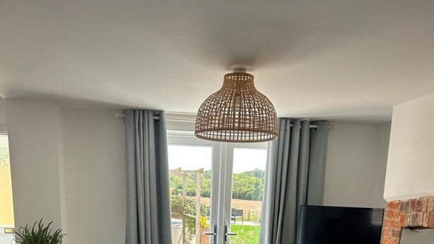 Ein Wohnzimmer mit einem großen Sofa, einem Fernseher auf einem Holzboden und Blick ins Freie durch eine Glastür.